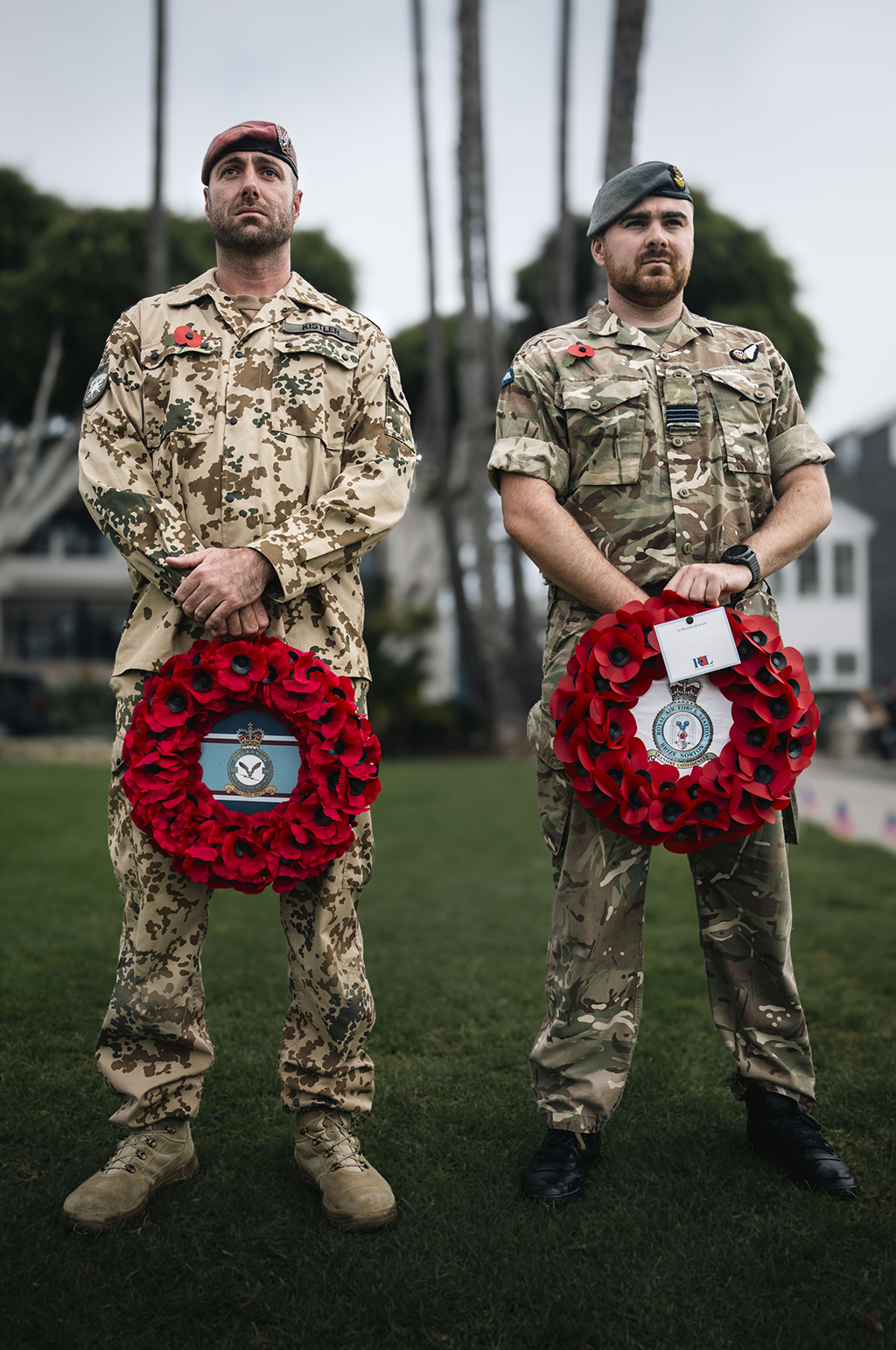 A member of the Royal Air Force Falcons Parachute Display Team, standing together with a Parachute School member from the German Army, wreaths in hand, during an Act of Remembrance Ceremony.